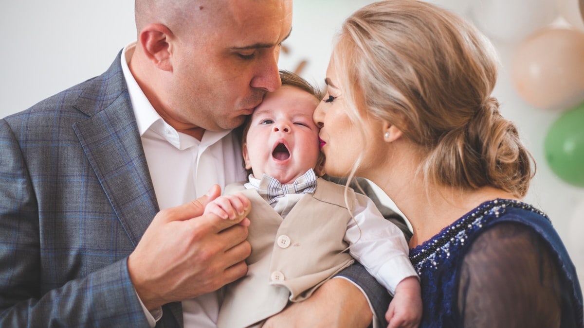 Father and mother holding and kissing son.